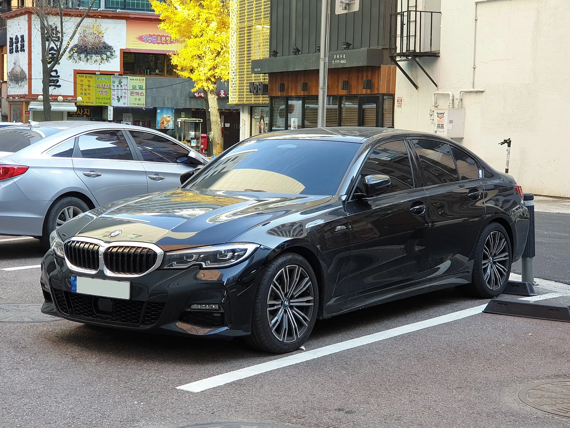 BMW סדרה 3 שחורה חונה ליד קו חניה לבן